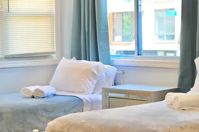 a room with two beds and a table with towels at 2-Bedroom Apartment 15 Minutes From Manhattan in LIC Astoria Queens
