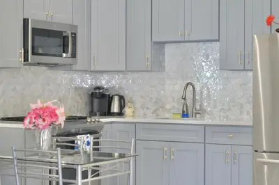 a kitchen with white cabinets and a glass table at 2-Bedroom Apartment 15 Minutes From Manhattan in LIC Astoria Queens