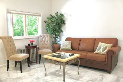 a living room with a brown couch and chairs at 2-Bedroom Apartment 15 Minutes From Manhattan in LIC Astoria Queens