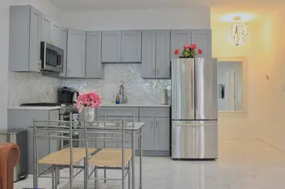 a kitchen with a refrigerator and a table with chairs at 2-Bedroom Apartment 15 Minutes From Manhattan in LIC Astoria Queens