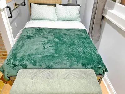 a bed with a green blanket on it at Corporate Housing, Upgraded Condo Downtown Hoboken in Hoboken