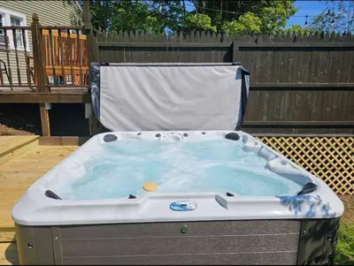a hot tub sitting on a deck in a backyard at Cozy Cottage House - Pool & Hot Tub in Liberty