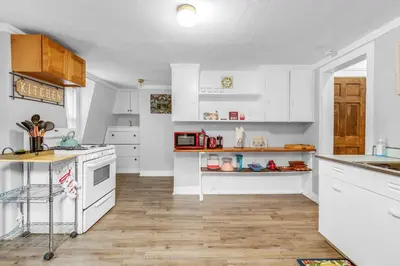 a kitchen with white cabinets and a wooden floor at Historic Studio Near Trinity College with Fast WiFi in Hartford