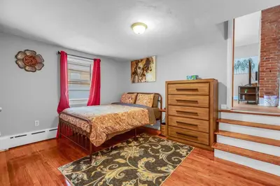 a bedroom with a bed and a dresser and a staircase at City Charm Walk to Trinity & Hospital with Parking in Hartford