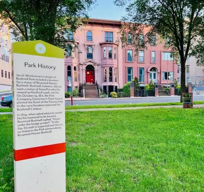 a park history sign in front of a pink building at City Charm Walk to Trinity & Hospital with Parking in Hartford