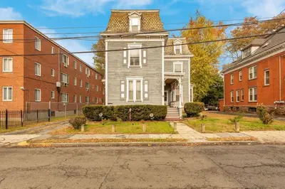 a gray house with a tower on a street at City Charm Walk to Trinity & Hospital with Parking in Hartford