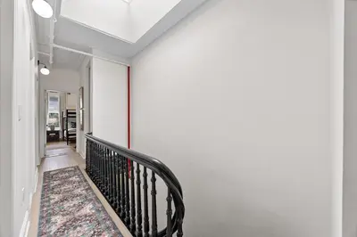 a hallway with a staircase with a black rail at 3BR Brownstone near Subway & Columbia Uni in New York
