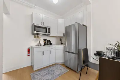 a kitchen with white cabinets and a stainless steel refrigerator at 3BR Brownstone near Subway & Columbia Uni in New York