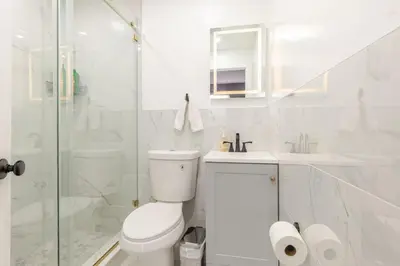 a white bathroom with a toilet and a shower at Modern 2 Bedroom in Black Rock in Bridgeport