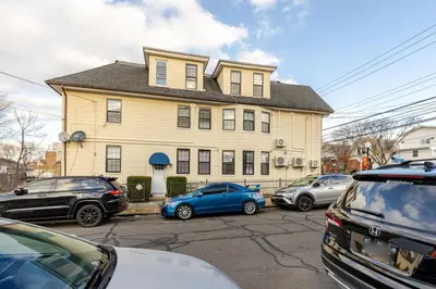 a large yellow house with cars parked in front of it at Modern 2 Bedroom in Black Rock in Bridgeport