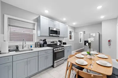 a kitchen with a table and a kitchen with white cabinets at The Hillside | Full House | Parking | Near EWR-NYC in Newark