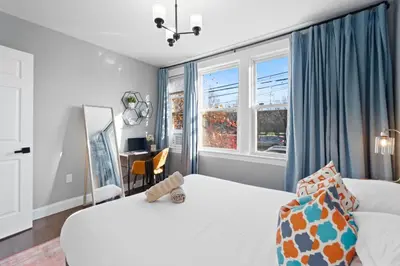 a bedroom with two beds and a desk and windows at Urban Charm | Near EWR Airport Easy Access to NYC in Newark