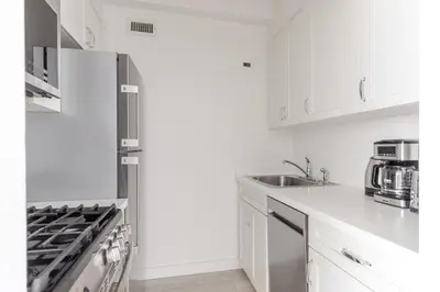 a kitchen with white cabinets and a refrigerator at Blueground Midtown East doorman nr MoMA NYC-1786 in New York