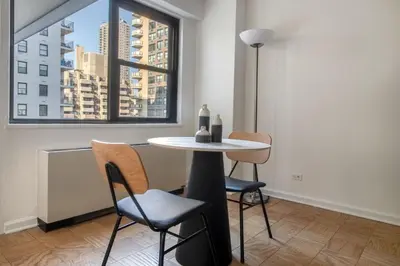 a table and chairs in a room with a window at Blueground Yorkville pool nr Central Park NYC-1329 in New York