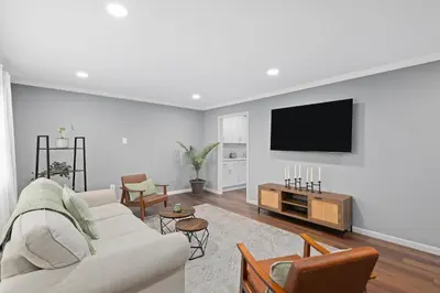 a living room with a couch and a tv on a wall at Cozy Home, 17 min from NYC, 2 Parking Spaces in Ridgefield Park