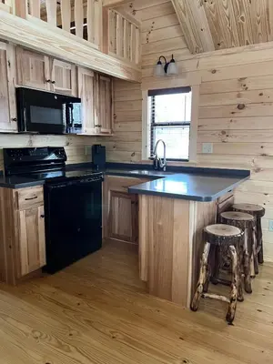 a kitchen with a black island in a log cabin at Tiny Cabin #1 by Windham NY Escape 'Catskill Gem' in Hensonville