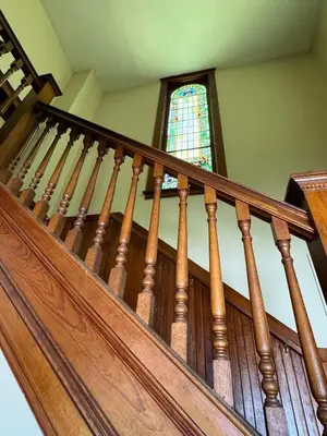 a wooden staircase with a stained glass window at The Pulpit House