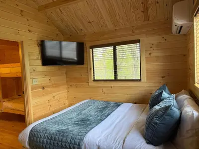 a bedroom with a bed and a flat screen tv at Tiny Cabin #2 by Windham NY Escape 'Cozy Stay' in Hensonville