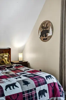 a bedroom with a bed with a bear quilt at Hideout Pocono Chalet in Lake Ariel