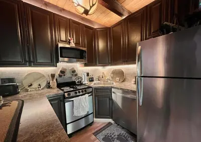 a kitchen with wooden cabinets and a stainless steel refrigerator at Hideout Pocono Chalet in Lake Ariel