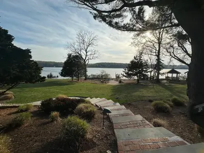 a garden with a pathway and a view of the water at Waterfront Paradise in St James in Nissequogue