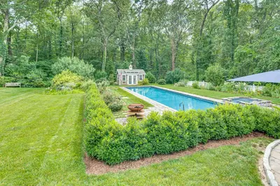 a backyard with a swimming pool and a house at Pool, Sunroom and Gardens Luxe Sandy Hook Home!