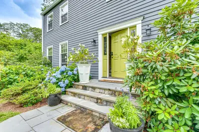 a home with a yellow door and stairs at Pool, Sunroom and Gardens Luxe Sandy Hook Home!