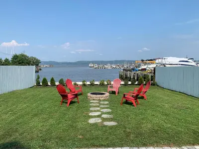 a group of red chairs sitting on the grass near the water at Waterfront Luxury in Town in Piermont