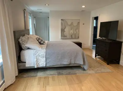 a bedroom with a bed with a dresser and a television at Waterfront Luxury in Town in Piermont
