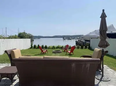 a patio with a couch and chairs and an umbrella at Waterfront Luxury in Town in Piermont