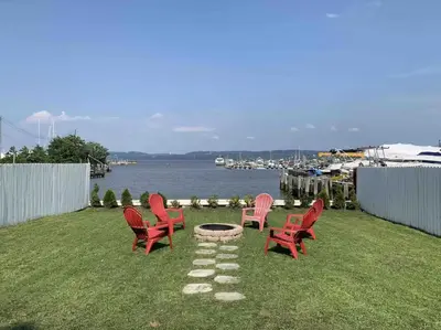a group of red chairs and a fire pit on a lawn at Waterfront Luxury in Town in Piermont