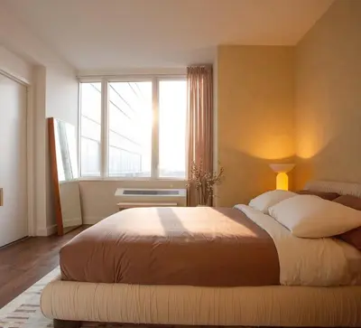 a bedroom with a large bed with a large window at Modern Designer Stunning Hudson Views Corner Unit in New York