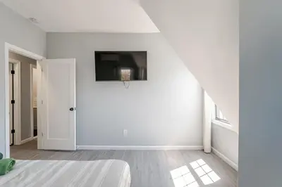 a white room with a bed and a tv on the wall at Modern House in Black Rock in Bridgeport