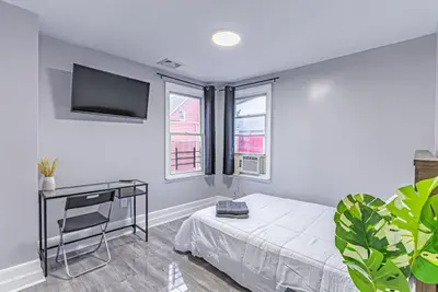 a bedroom with a bed and a desk and windows at 6Br 2bth NYC Penn Station NYC USA Mall EWR in Newark