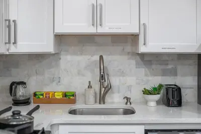 a kitchen with white cabinets and a sink at Modern Condo with Private Porch, Mins to NYC in Jersey City