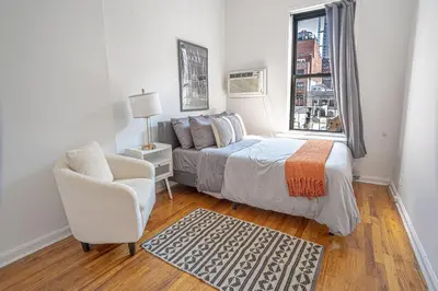 a bedroom with a bed and a chair and a window at Chic 2BD Upper East Side Retreat in New York