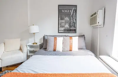 a small bedroom with a bed and a chair at Chic 2BD Upper East Side Retreat in New York