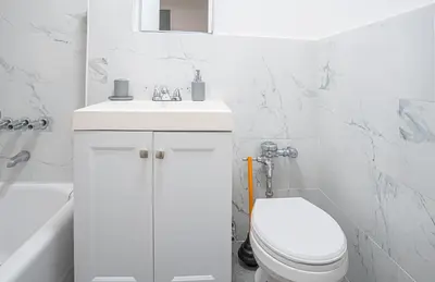 a white bathroom with a toilet and a sink at Chic 2BD Upper East Side Retreat in New York