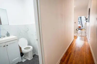 a bathroom with a white toilet and a wooden floor at Chic 2BD Upper East Side Retreat in New York