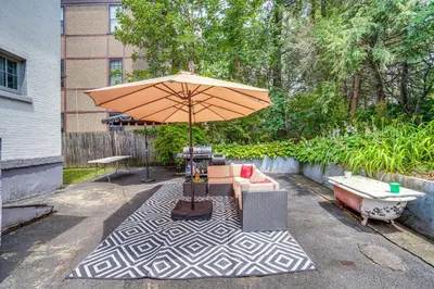 a patio with a table with an umbrella and chairs at Steps to Union College Home with Shared Yard! in Schenectady