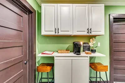 a kitchen with white cabinets and a counter with stools at Walk to Nott Memorial Studious Retreat Near Eats in Schenectady