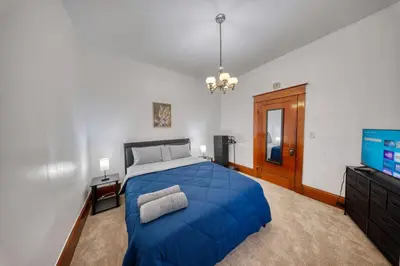 a bedroom with a blue bed and a flat screen tv at Charming 2-Bedroom, 1-Bath Getaway in Carbondale