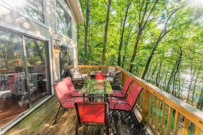 a porch with chairs and a table on a deck at Switch to hosting Peaceful Lakefront Stay, HotTub, Fireplace, Kayaks in East Stroudsburg