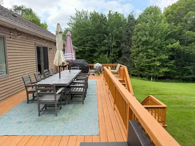 a deck with a table and chairs and an umbrella at Mountain Modern Escape - EV Charger - 5BDRM in Hensonville