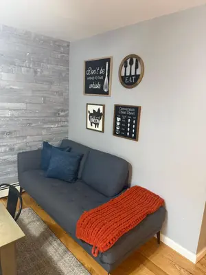 a living room with a blue couch and a clock at Mountain Modern Escape - EV Charger - 5BDRM in Hensonville
