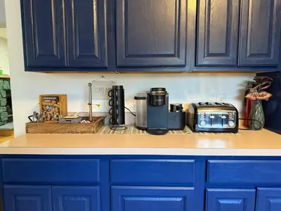 a kitchen with blue cabinets and a toaster on a counter at Mountain Modern Escape - EV Charger - 5BDRM in Hensonville