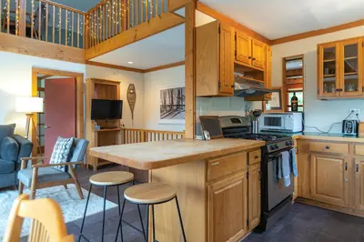 a kitchen with wooden cabinets and a kitchen island with stools at MtSnow , HotTub, Pool, Air Hockey,Ping Pong, Darts in Wilmington