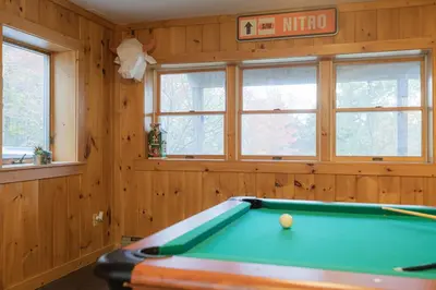 a pool table in a room with wooden walls and windows at MtSnow , HotTub, Pool, Air Hockey,Ping Pong, Darts in Wilmington