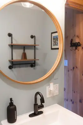 a bathroom sink with a round mirror above it at MtSnow , HotTub, Pool, Air Hockey,Ping Pong, Darts in Wilmington