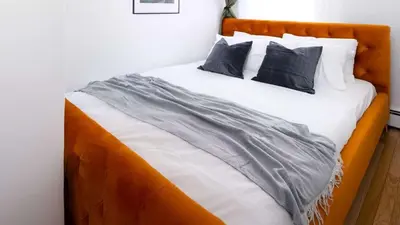 a bed with an orange headboard and two pillows at Spacious 3BR Retreat Near Times Square in New York